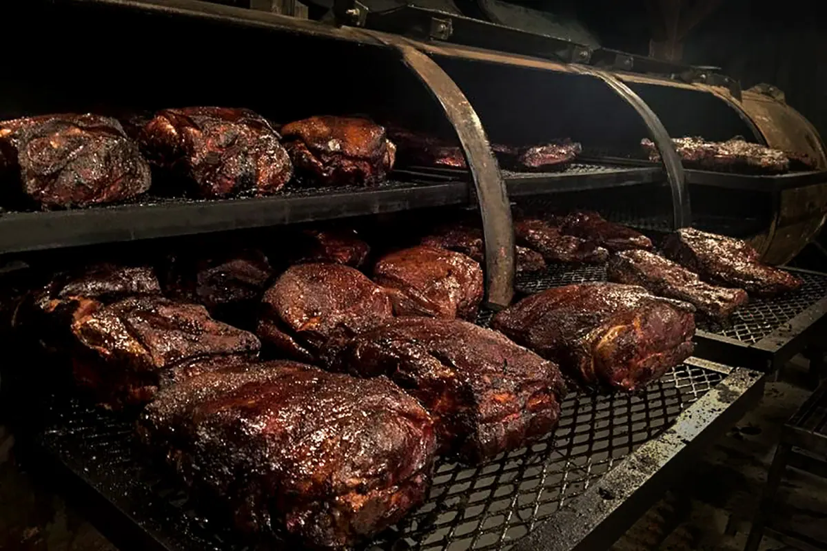 Briskets and pork shoulders on the racks of the smoker