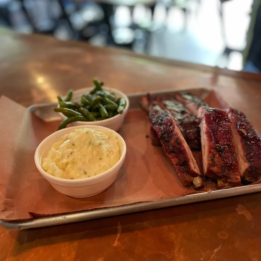 A platter of ribs with green beans and potato salad