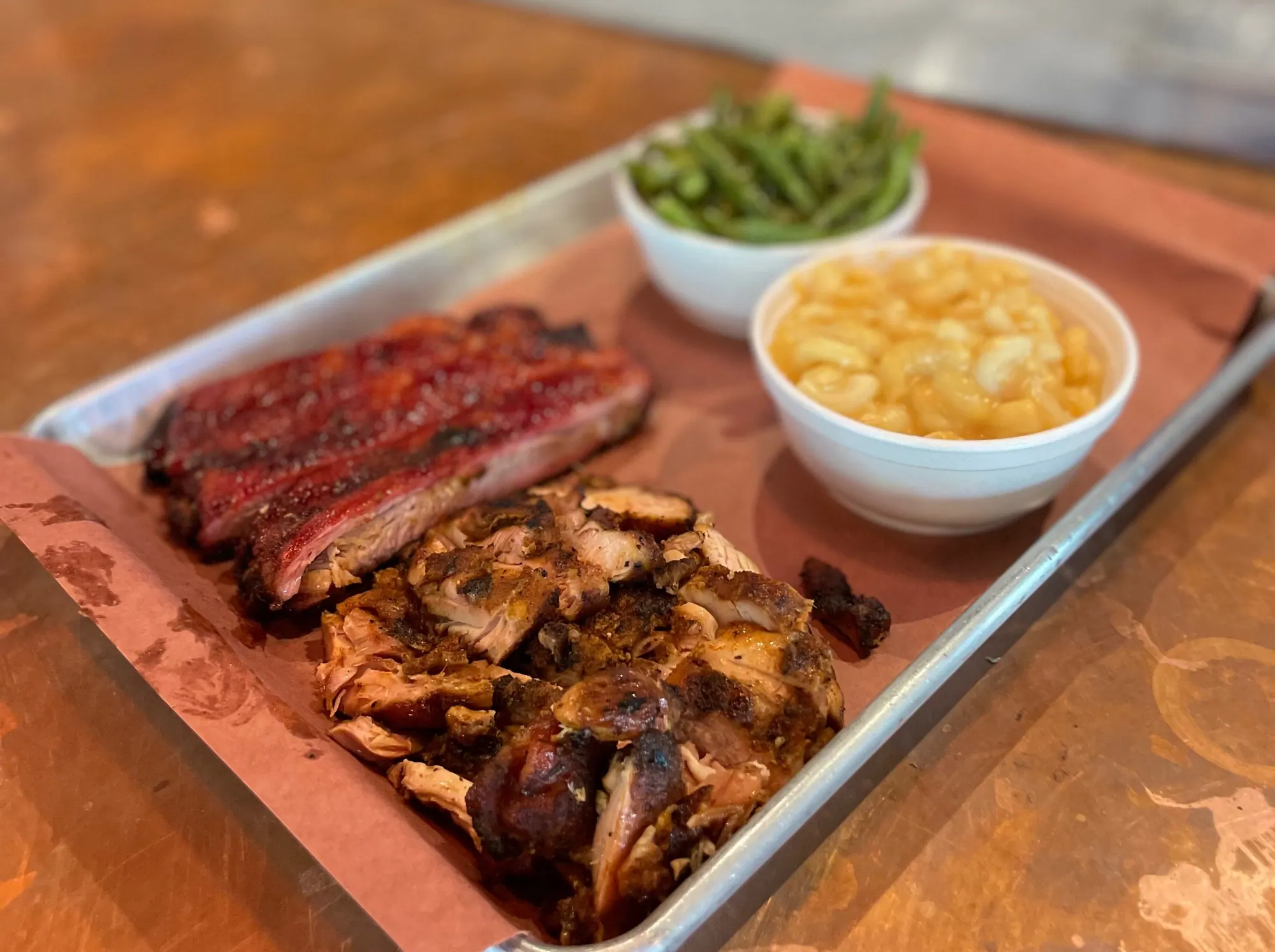 A tray of ribs and grilled chicken with green beans and mac and cheese on butcher paper